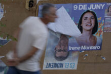 Una persona para ante una valla con carteles electorales de la candidata de Podemos a las elecciones europeas, Irene Montero, para las próximas elecciones del 9 de junio al Parlamento Europeo sobre otros del líder del PP, Alberto Núñez Feijóo, para las pasadas elecciones presidenciales.