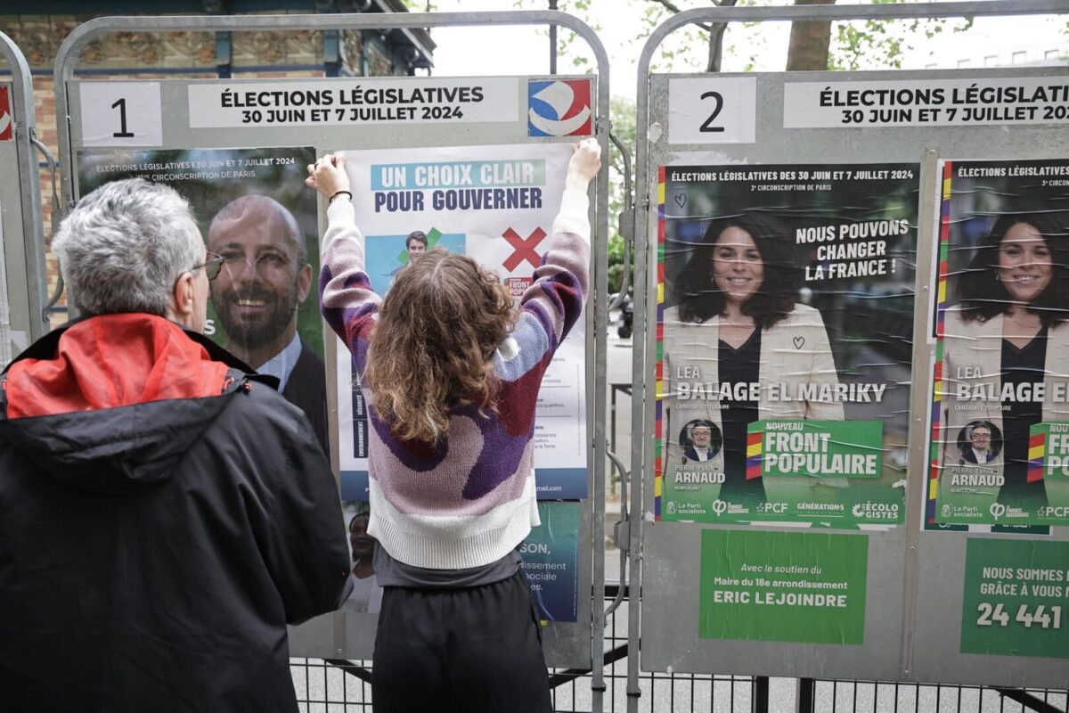 Voluntarios reemplazan carteles de campaña durante la segunda vuelta de las elecciones parlamentarias francesas en París, Francia