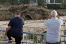 Varios vecinos contemplan el puente arrastrado por el agua en Ribarroja del Turia (Valencia)