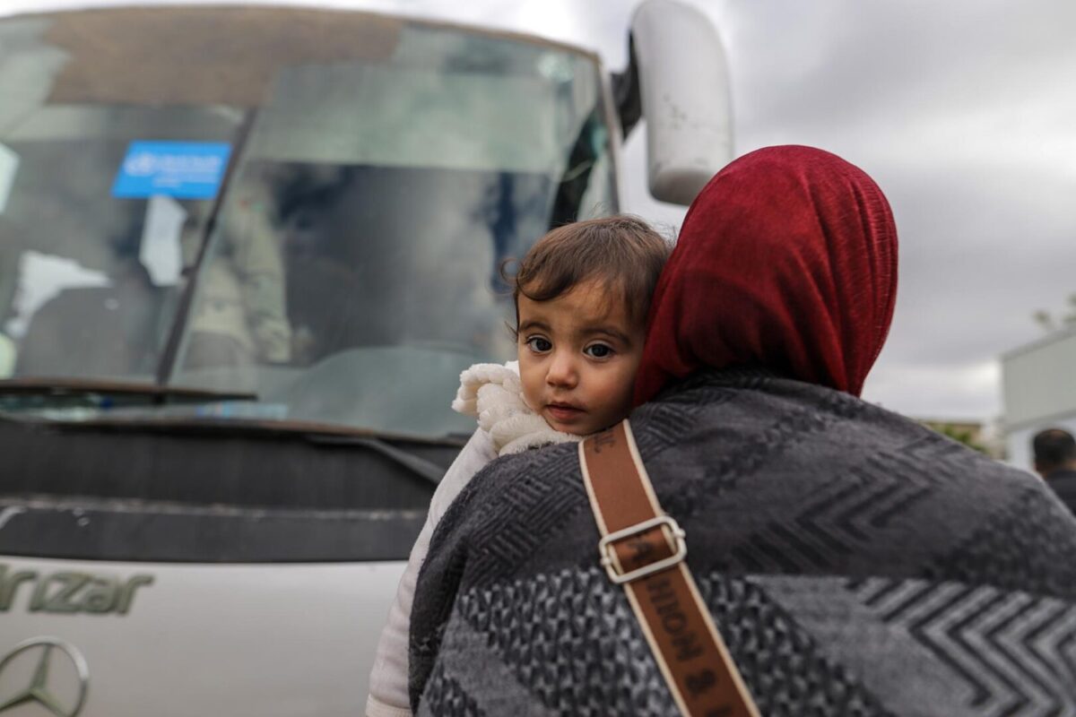 Una mujer con un niño en brazos se prepara para salir de la Franja de Gaza hacia el paso fronterizo de Rafah